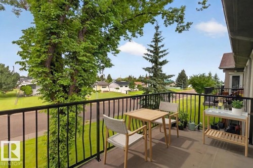 Exterior balcony with dark railing and a wood-finish floor - #205 6315 135 Av Nw, Edmonton, AB - Outdoor With Balcony With Exterior