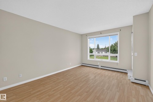Wood-finish flooring with a neutral wall palette - #205 6315 135 Av Nw, Edmonton, AB - Indoor Photo Showing Other Room
