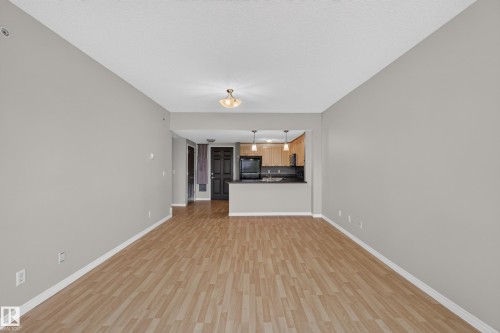 Wood-finish flooring throughout, complemented by light grey walls and white trim - #205 6315 135 Av Nw, Edmonton, AB - Indoor Photo Showing Other Room