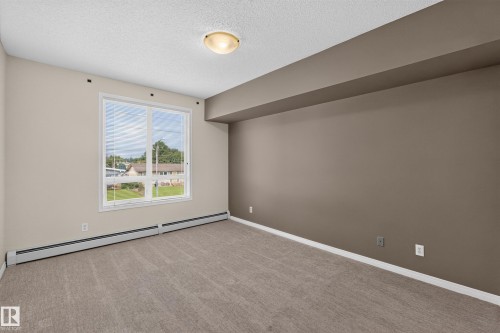 Carpeted interior with neutral wall colors and a single window - #205 6315 135 Av Nw, Edmonton, AB - Indoor Photo Showing Other Room