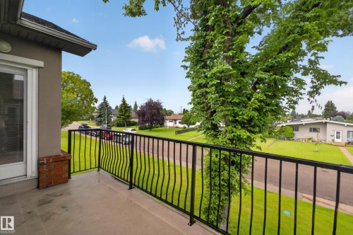 Balcony with black wrought iron railing, stucco exterior, and a white exterior door - #205 6315 135 Av Nw, Edmonton, AB - Outdoor With Balcony