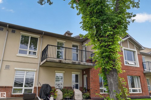 Multi-story exterior with stucco and brick siding, multiple windows, and a private balcony with black railings - #205 6315 135 Av Nw, Edmonton, AB - Outdoor With Balcony