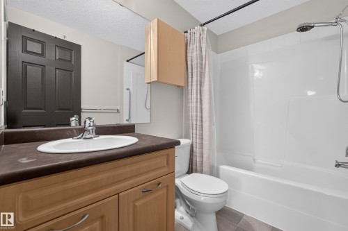 Vanity with wood-finish cabinetry, integrated sink, and chrome faucet - #205 6315 135 Av Nw, Edmonton, AB - Indoor Photo Showing Bathroom
