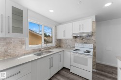 White cabinetry with brushed nickel hardware, light-toned stone backsplash, dual-basin stainless steel sink, light gray countertops, and wood-finish flooring - 