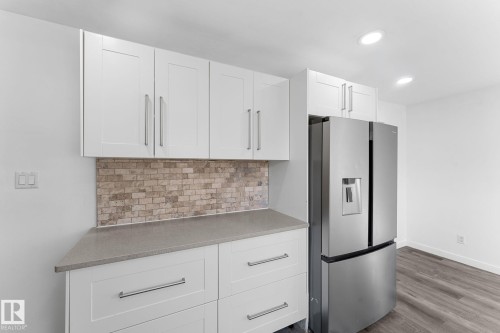 White shaker cabinetry, light-toned stone backsplash, gray countertop, and wood-finish flooring - 7823 136 Avenue Nw, Edmonton, AB - Indoor Photo Showing Kitchen