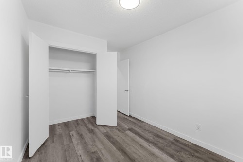 Recessed lighting fixture, wood-finish flooring, white walls, built-in closet with double hanging rods and shelf, white door with dark hardware - 7823 136 Avenue Nw, Edmonton, AB - Indoor Photo Showing Other Room