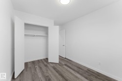 Recessed lighting fixture, wood-finish flooring, white walls, built-in closet with double hanging rods and shelf, white door with dark hardware - 