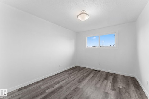 Recessed ceiling light fixture, white walls, wood-finish flooring, and a large window - 7823 136 Avenue Nw, Edmonton, AB - Indoor Photo Showing Other Room
