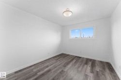 Recessed ceiling light fixture, white walls, wood-finish flooring, and a large window - 