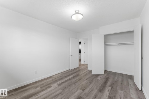 Wood-finish flooring, recessed ceiling light, white walls, double-door closet with hanging rods, and white trim - 7823 136 Avenue Nw, Edmonton, AB - Indoor Photo Showing Other Room