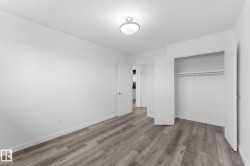 Wood-finish flooring, recessed ceiling light, white walls, double-door closet with hanging rods, and white trim - 