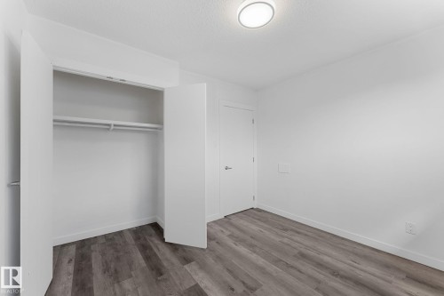 Wood-finish flooring, white walls, built-in closet with shelving and hanging rods, ceiling-mounted light fixture, and white interior doors - 7823 136 Avenue Nw, Edmonton, AB - Indoor Photo Showing Other Room