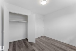 Wood-finish flooring, white walls, built-in closet with shelving and hanging rods, ceiling-mounted light fixture, and white interior doors - 