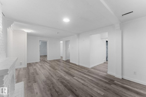 Wood-finish flooring throughout, recessed lighting, and a painted brick fireplace - 7823 136 Avenue Nw, Edmonton, AB - Indoor Photo Showing Other Room