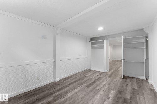 Wood-finish flooring throughout, recessed lighting, built-in shelving, white brick-style wainscoting, and a white interior door - 7823 136 Avenue Nw, Edmonton, AB - Indoor Photo Showing Other Room