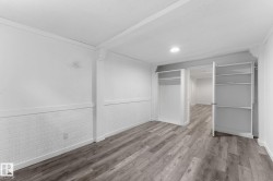 Wood-finish flooring throughout, recessed lighting, built-in shelving, white brick-style wainscoting, and a white interior door - 