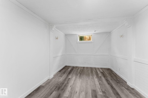 Wood-finish flooring with white baseboards, white brick-patterned wainscoting, and a single window - 7823 136 Avenue Nw, Edmonton, AB - Indoor Photo Showing Other Room