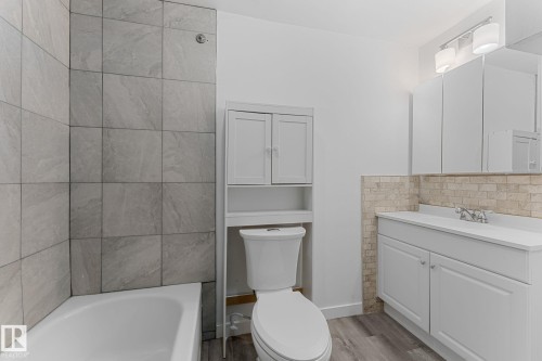 White vanity with an integrated sink, built-in storage cabinet, and stone tile backsplash - 7823 136 Avenue Nw, Edmonton, AB - Indoor Photo Showing Bathroom