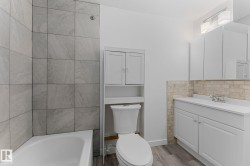 White vanity with an integrated sink, built-in storage cabinet, and stone tile backsplash - 