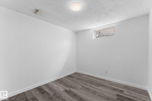 White painted walls, wood-finish flooring, and a flush mount ceiling light fixture - 7823 136 Avenue Nw, Edmonton, AB - Indoor Photo Showing Other Room