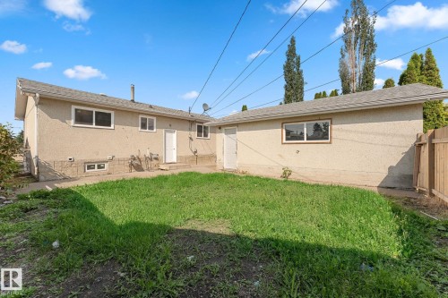 Expansive backyard featuring a grass area, stucco exterior, and a wood privacy fence - 7823 136 Avenue Nw, Edmonton, AB - Outdoor