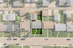 Street-facing property with a manicured lawn, two detached structures, and a partial concrete driveway - 
