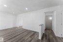 Recessed ceiling lighting, light gray wood-finish flooring, white painted walls, and a gray-capped half-wall - 7823 136 Avenue Nw, Edmonton, AB  - Indoor Photo Showing Other Room 