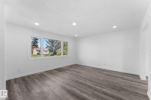 Spacious room featuring wood-finish flooring, recessed lighting, and a large multi-pane window - 7823 136 Avenue Nw, Edmonton, AB - Indoor Photo Showing Other Room
