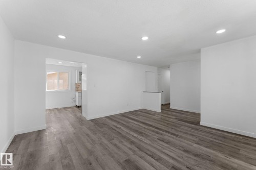 Spacious open-concept living area featuring engineered wood-finish flooring throughout, recessed ceiling lighting, and clean white walls - 7823 136 Avenue Nw, Edmonton, AB - Indoor Photo Showing Other Room