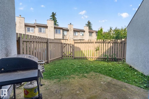 Enclosed backyard featuring a privacy fence with a gate, concrete patio, and garden area - 17775 95 Street Nw, Edmonton, AB 