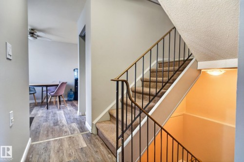 Carpeted staircase with black metal railings and a wood-finish handrail - 17775 95 Street Nw, Edmonton, AB 