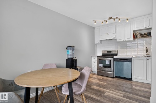 Kitchenette featuring white shaker cabinetry, stainless steel appliances, white subway tile backsplash, track lighting, and wood-finish flooring - 17775 95 Street Nw, Edmonton, AB 