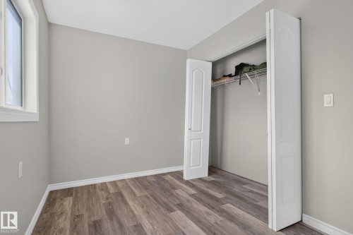 Neutral wall palette, wood-finish flooring, white window trim, and a bi-fold door closet with wire shelving - 17775 95 Street Nw, Edmonton, AB 