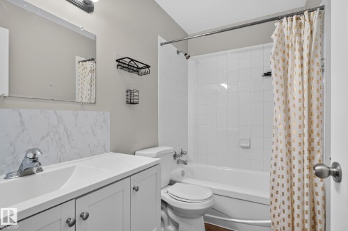 White vanity with cabinet storage, integrated sink, chrome faucet, and a large wall mirror - 17775 95 Street Nw, Edmonton, AB 