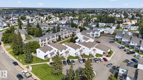 Aerial perspective showcasing a residential community with multiple townhome buildings, paved parking areas, and mature trees - 17775 95 Street Nw, Edmonton, AB 
