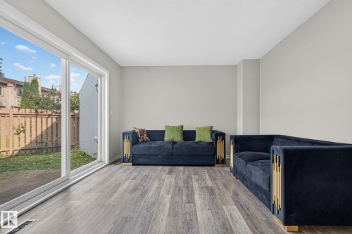 Spacious interior featuring light gray walls, wood-finish flooring, and sliding glass doors opening to a fenced yard - 17775 95 Street Nw, Edmonton, AB 