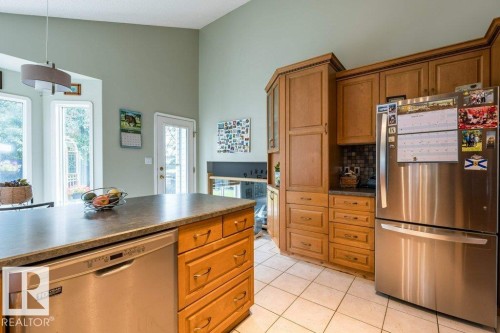 Kitchen featuring light wood cabinetry, stainless steel appliances, a center island with integrated dishwasher, and tiled flooring - 4705 43 Street, Beaumont, AB 