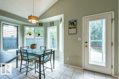 Vaulted ceiling with a drum pendant light, bay window with multiple panes, tile flooring, and a glass-paneled exterior door - 4705 43 Street, Beaumont, AB 