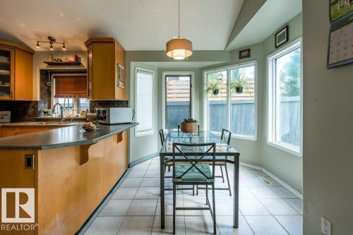 Kitchen with light wood-finish cabinetry, dark countertop, and tiled backsplash - 4705 43 Street, Beaumont, AB 