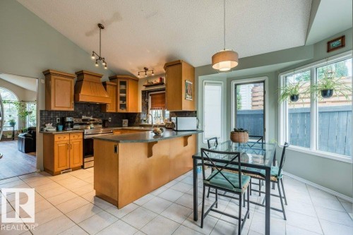 Vaulted ceiling, wood cabinetry, tile flooring, kitchen island, and a bay window - 4705 43 Street, Beaumont, AB 
