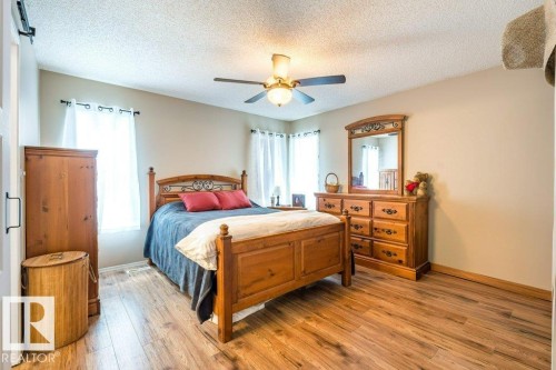 Wood-finish flooring, ceiling fan with integrated lighting, multiple windows with white window treatments, and light-toned walls - 4705 43 Street, Beaumont, AB 