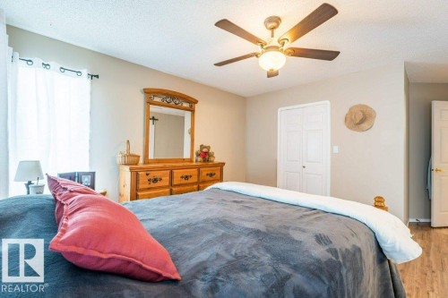 Ceiling fan with integrated lighting, wood-finish flooring, white bi-fold closet doors, and light-colored walls - 4705 43 Street, Beaumont, AB 