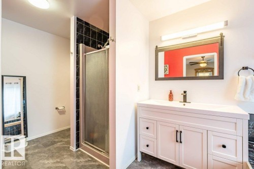 White vanity with integrated sink, black faucet, and rectangular mirror with decorative frame - 4705 43 Street, Beaumont, AB 