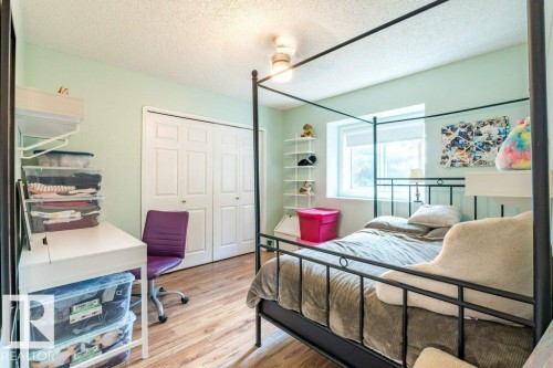 Wood-finish flooring, bi-fold closet doors, window with roller blind, wall-mounted shelving unit, and a ceiling-mounted light fixture - 4705 43 Street, Beaumont, AB 