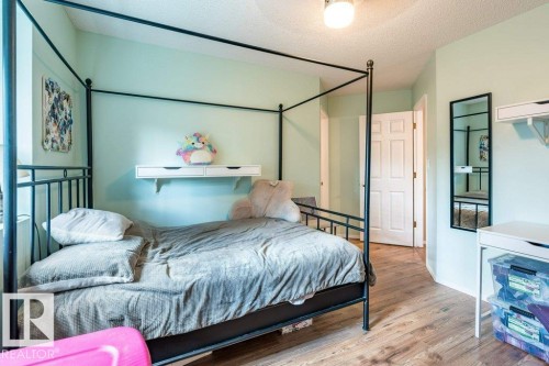 Wood-finish flooring, ceiling-mounted light fixture, white interior door, wall-mounted shelf, and a wall-mounted mirror - 4705 43 Street, Beaumont, AB 