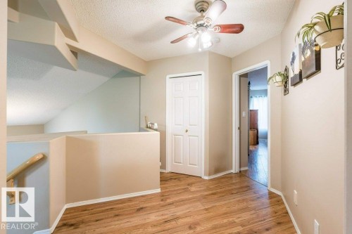Wood-finish flooring, ceiling fan with integrated lighting, paneled interior doors, and a light neutral color palette throughout - 4705 43 Street, Beaumont, AB 