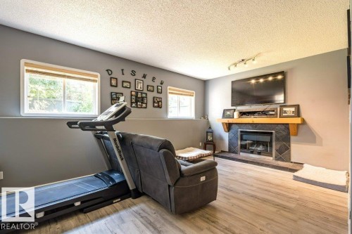 Recessed fireplace with slate tile surround, wood-finish mantel, and wood-finish flooring - 4705 43 Street, Beaumont, AB 