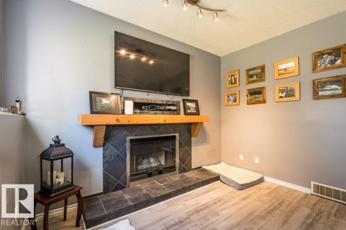 Fireplace with slate tile surround, wood mantel, and wood-finish flooring - 4705 43 Street, Beaumont, AB 