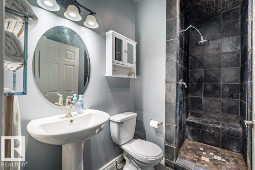 Pedestal sink with chrome faucet, oval mirror, and three-light vanity fixture - 4705 43 Street, Beaumont, AB 