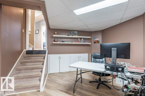 Carpeted staircase with white trim, wood-finish flooring, built-in white cabinetry, white floating shelves, and a drop ceiling with integrated lighting - 4705 43 Street, Beaumont, AB 